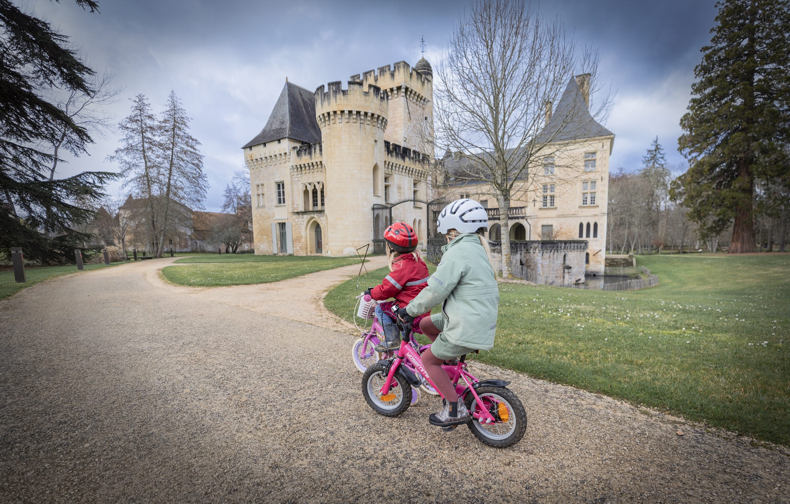 Två barn som cyklar framför ett franskt slott